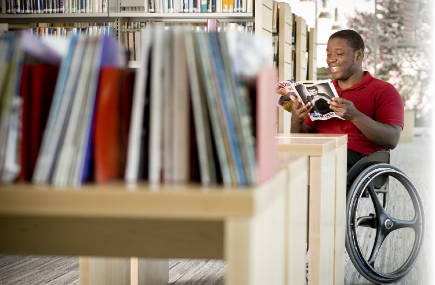 Man in wheelchair reading magazine at the Cambridge Library